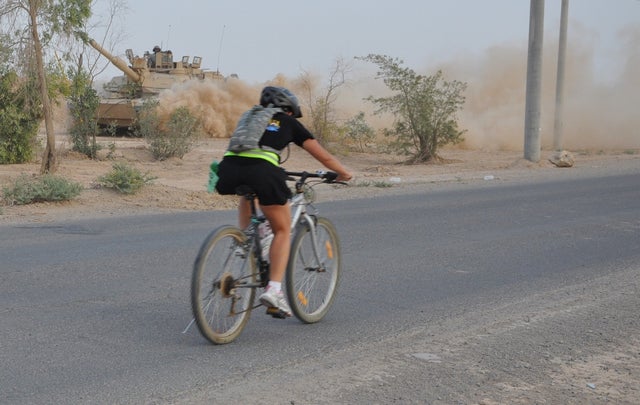 Iraq Triathlon Bike Staff Sgt. Patricia McCarthy, badging non-commissioned officer, Headquarters and Headquarters Co., 181st Brigade Support Battalion, and Olympia, Wash. native, rides past a M1A2 Abram tank during the Bushmaster’s Triathlon at Contingency Operation Base Q-West, Iraq, June 28. The race consisted of a 400-meter swim, an 11K bike and a 3K run.