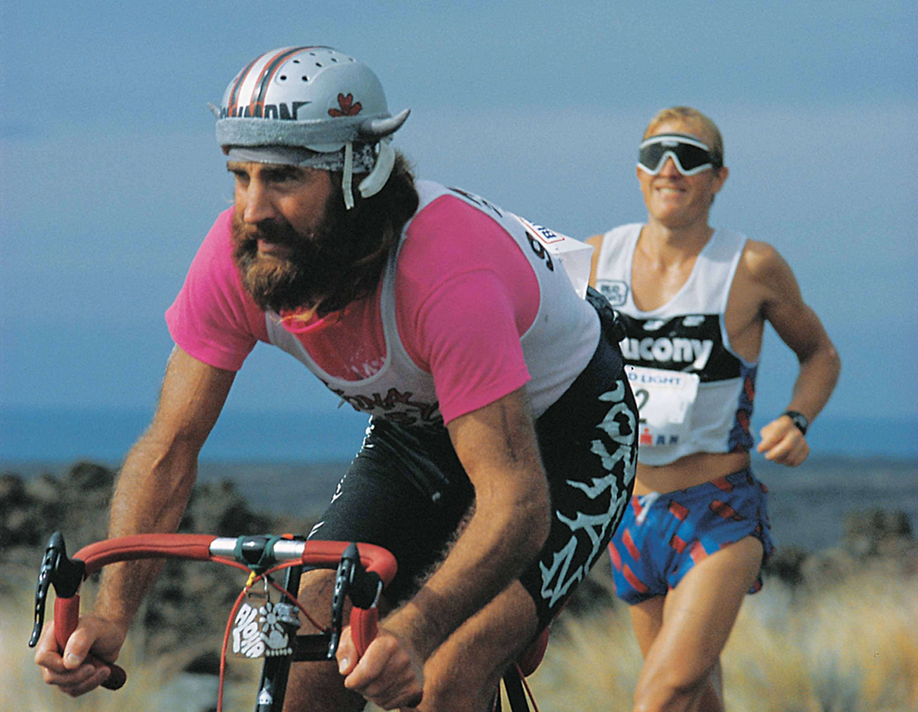Eventual winner Scott Tinley runs toward the turnaround as Ken Shirk, aka Cowman, finishes the bike in this classic image of the 1985 race, the last year of amateurism at Ironman Hawaii. Photo: Lois Schwartz