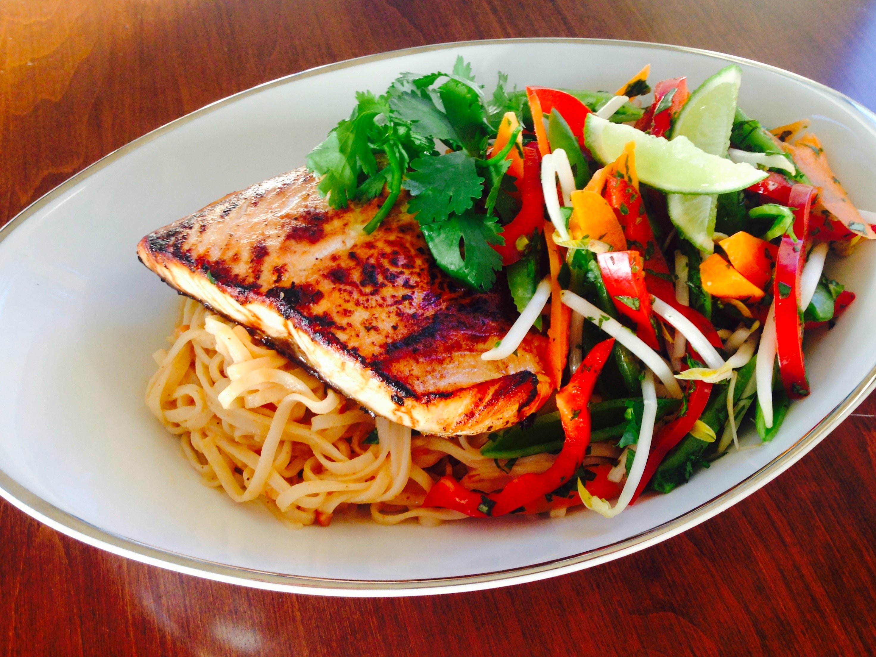 Thai peanut noodles and veggie saw, topped with salmon.