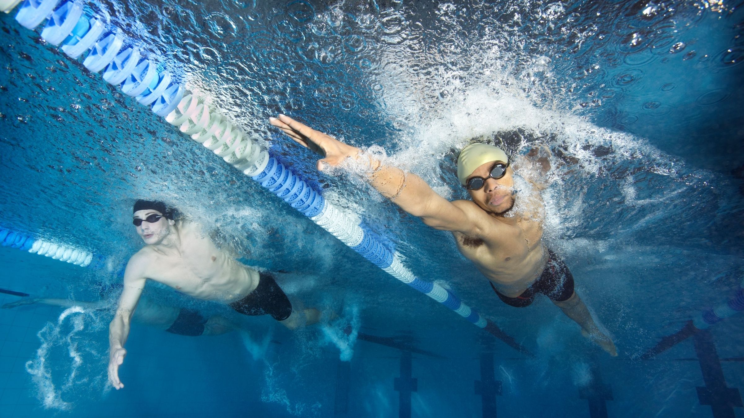 An underwater shot of two men swimming freestyle, with a lane divider between during a Weekend Swim Workout from Triathlete.