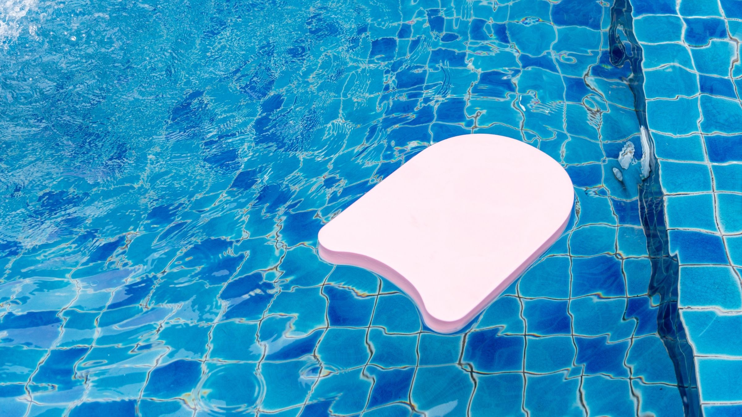 A pink kickboard floats in a swimming pool