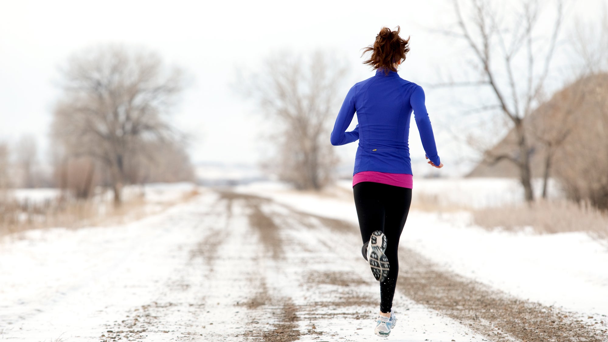 A triathlete runs on a snow-covered path during an anaerobic endurance booster One-Hour Workout.