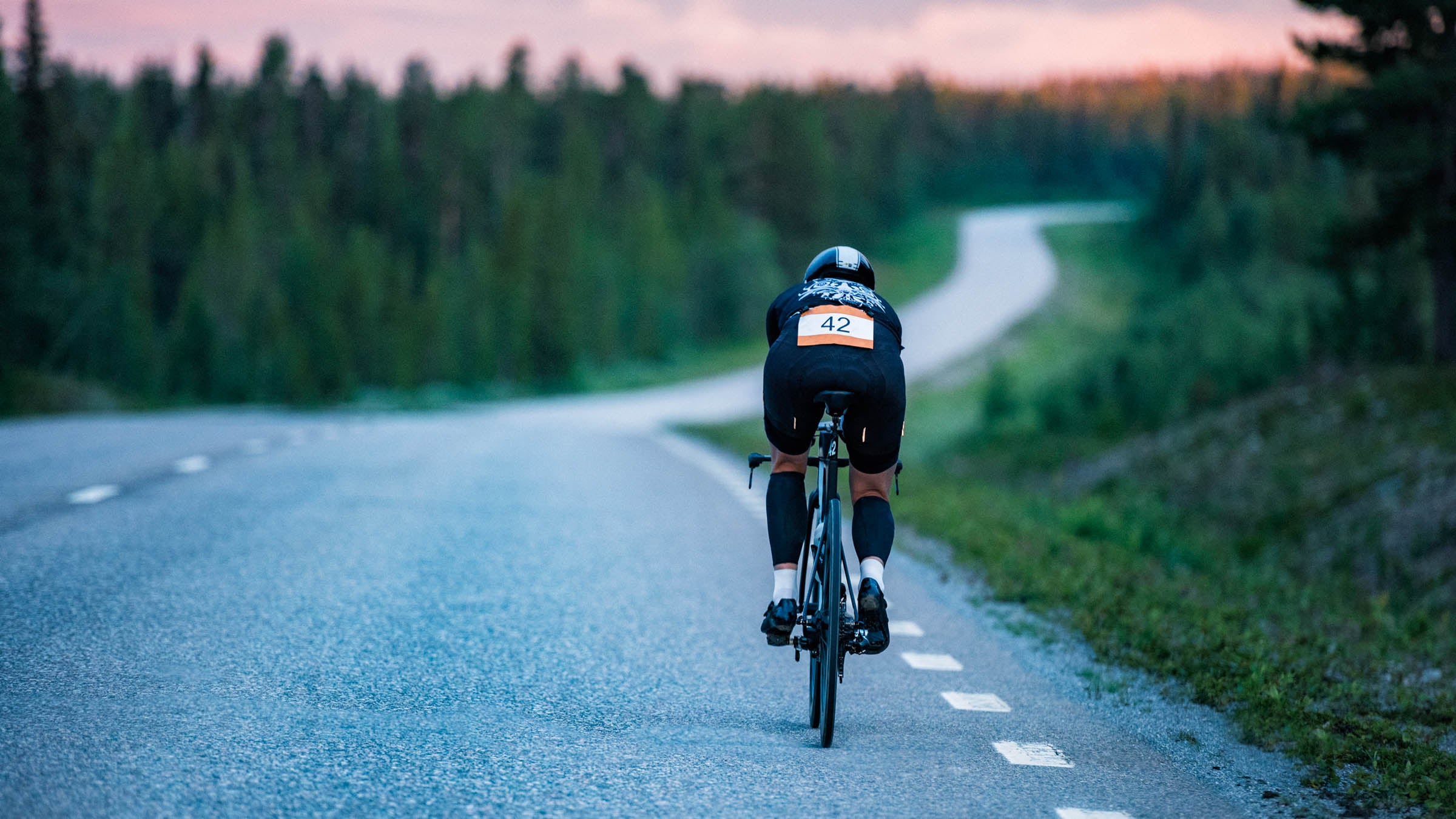 Triathlete cycling downhill at sunset