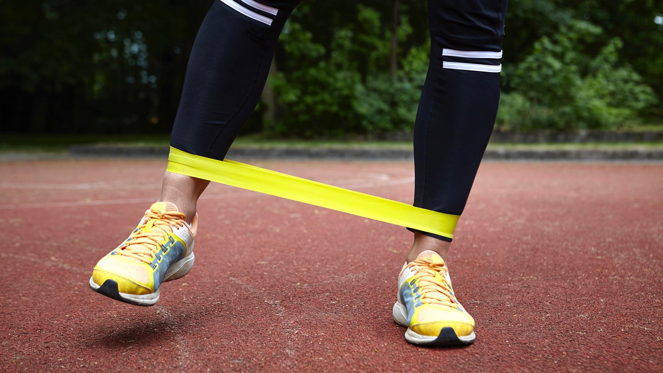 Runner's legs with a resistance band around the ankles as they engage in strength training for injury prevention