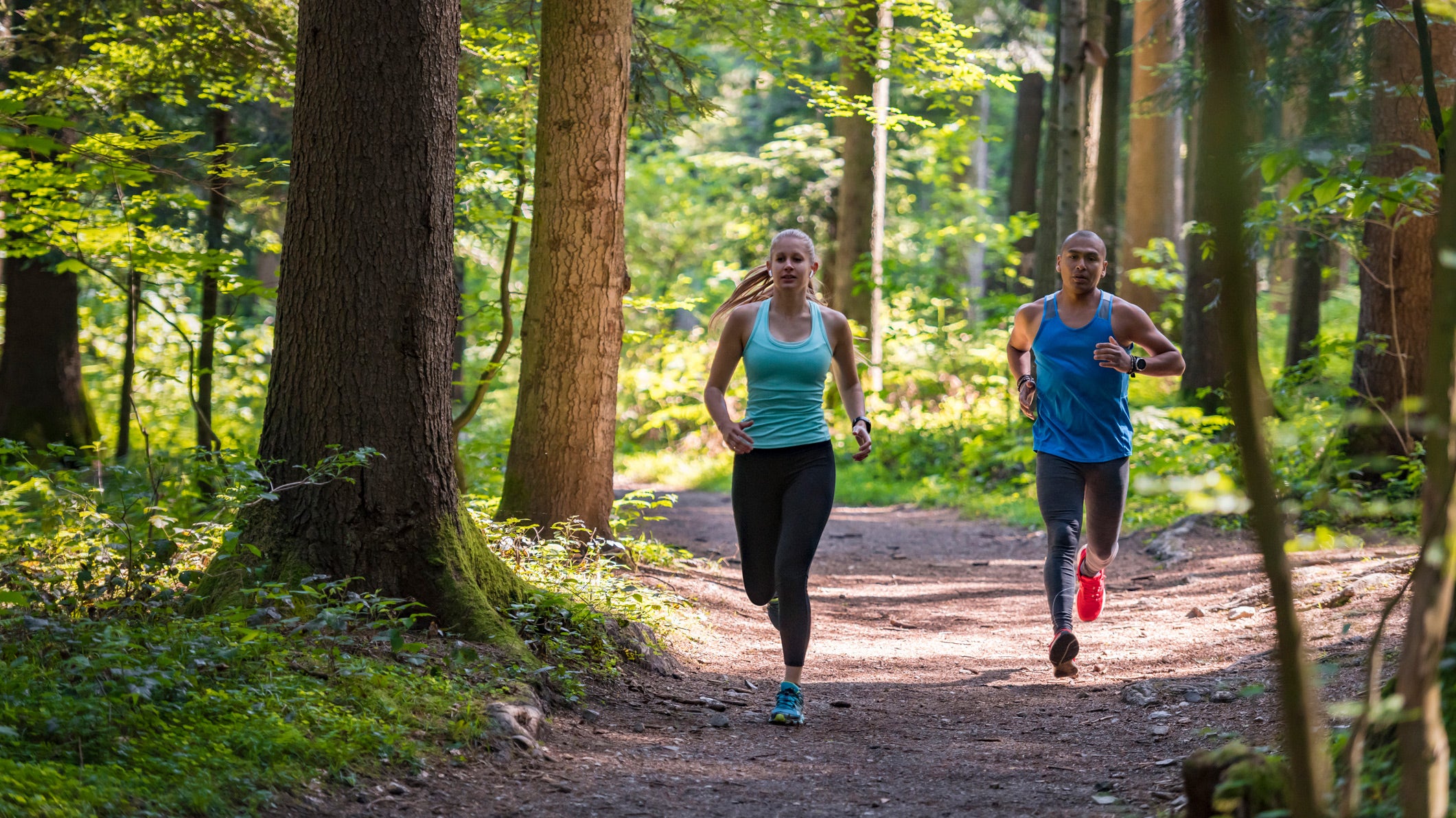 Two runners on a trail run surface. When it comes to run surfaces, trails are a great option.