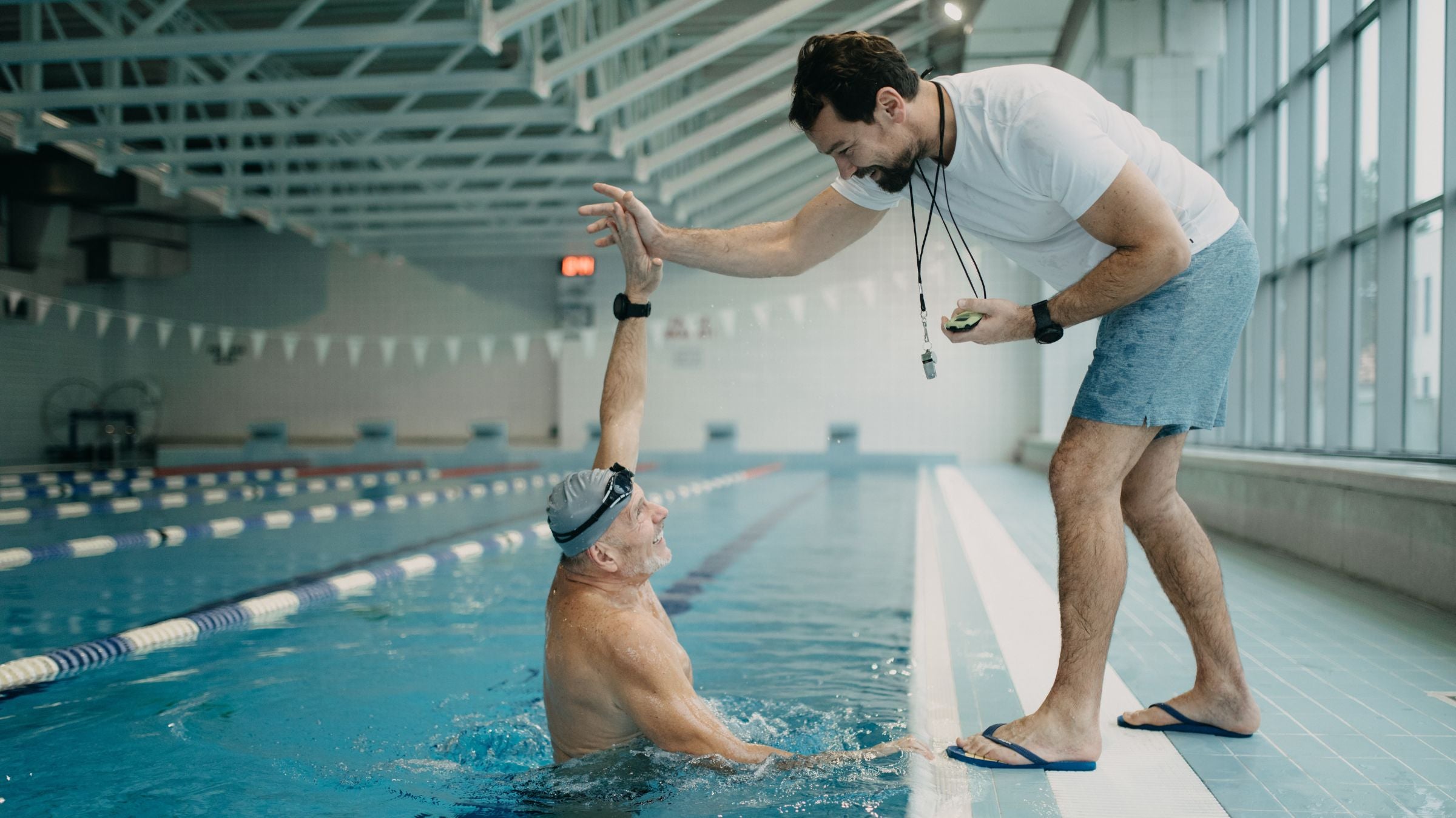 a swimmer high-fives his coach after doing a 500 meter test set