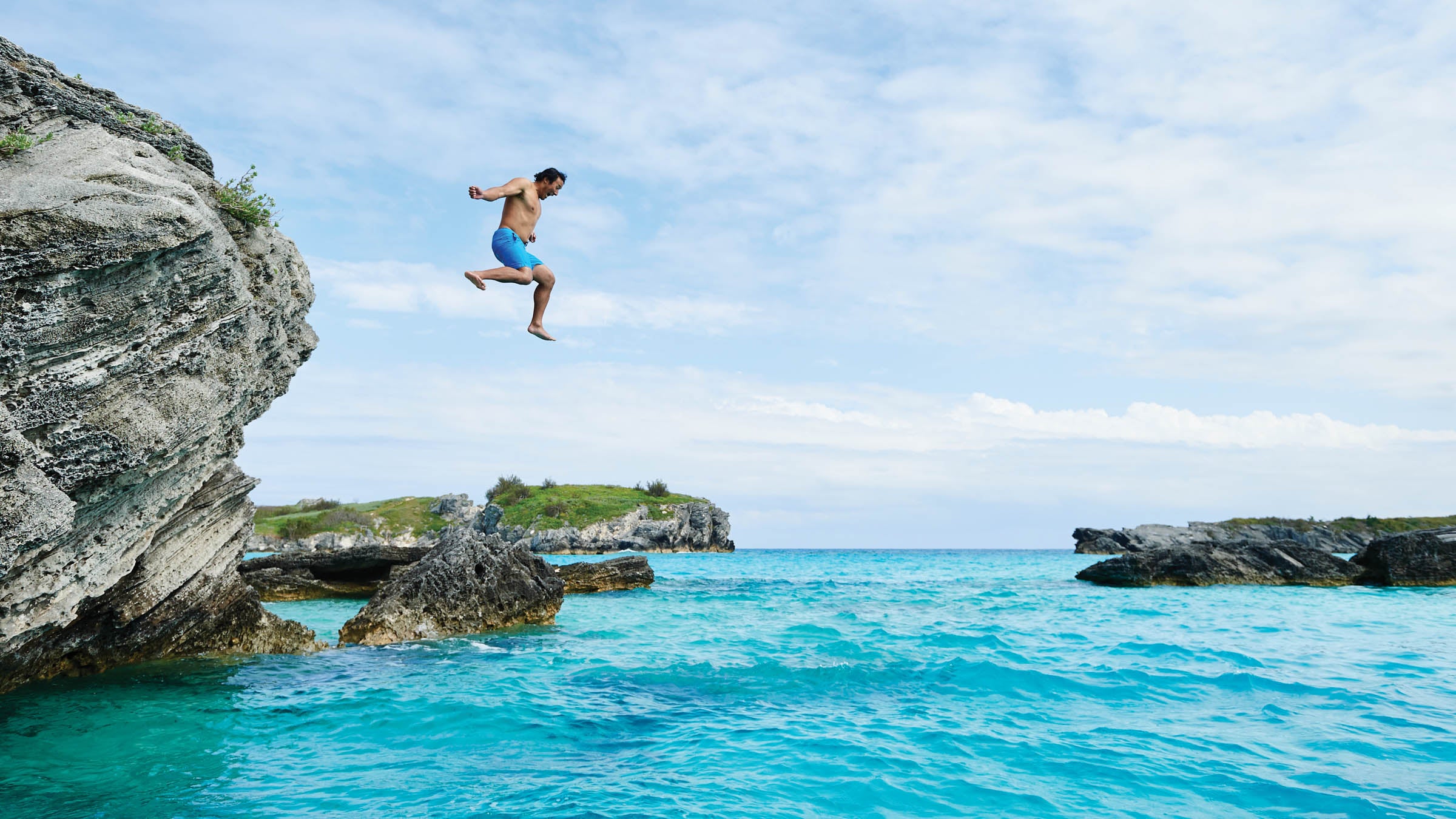 Man jumping off a cliff into the ocean