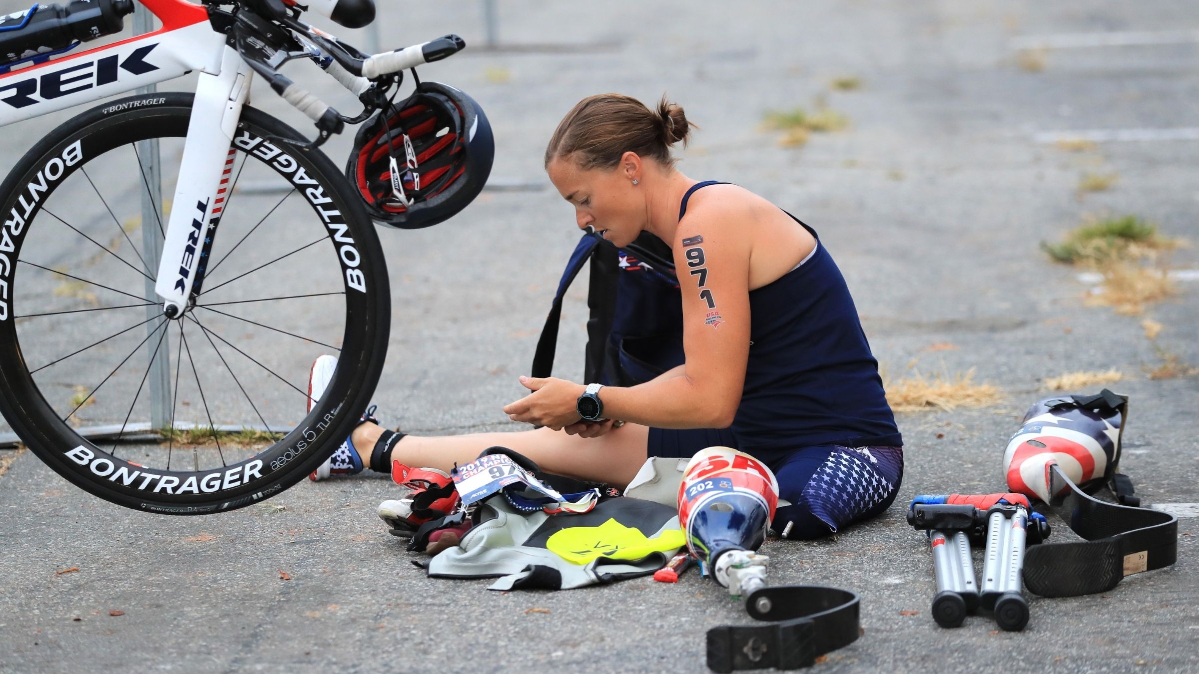 Melissa Stockwell, a paratriathlete, sits next to her bike in transition, surrounded by gear including a prosthetic leg.