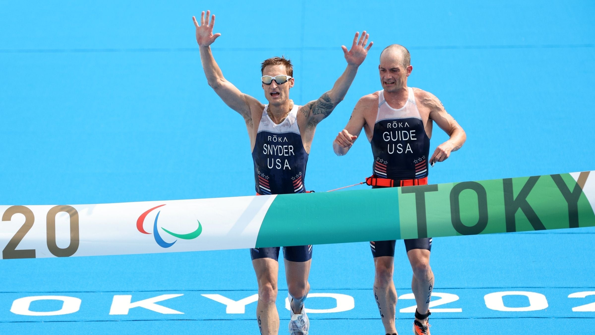 Brad Snyder and guide Greg Billington of Team United States react as they cross the finish line to win the gold medal during the men's PTVI Triathlon on day 4 of the Tokyo 2020 Paralympic Games at Odaiba Marine Park on August 28, 2021 in Tokyo, Japan.