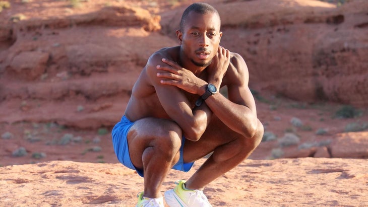 Sam Holness, the first openly autistic person to compete at a triathlon world championship, crouches as he looks at the camera. He is wearing running shorts and shoes.