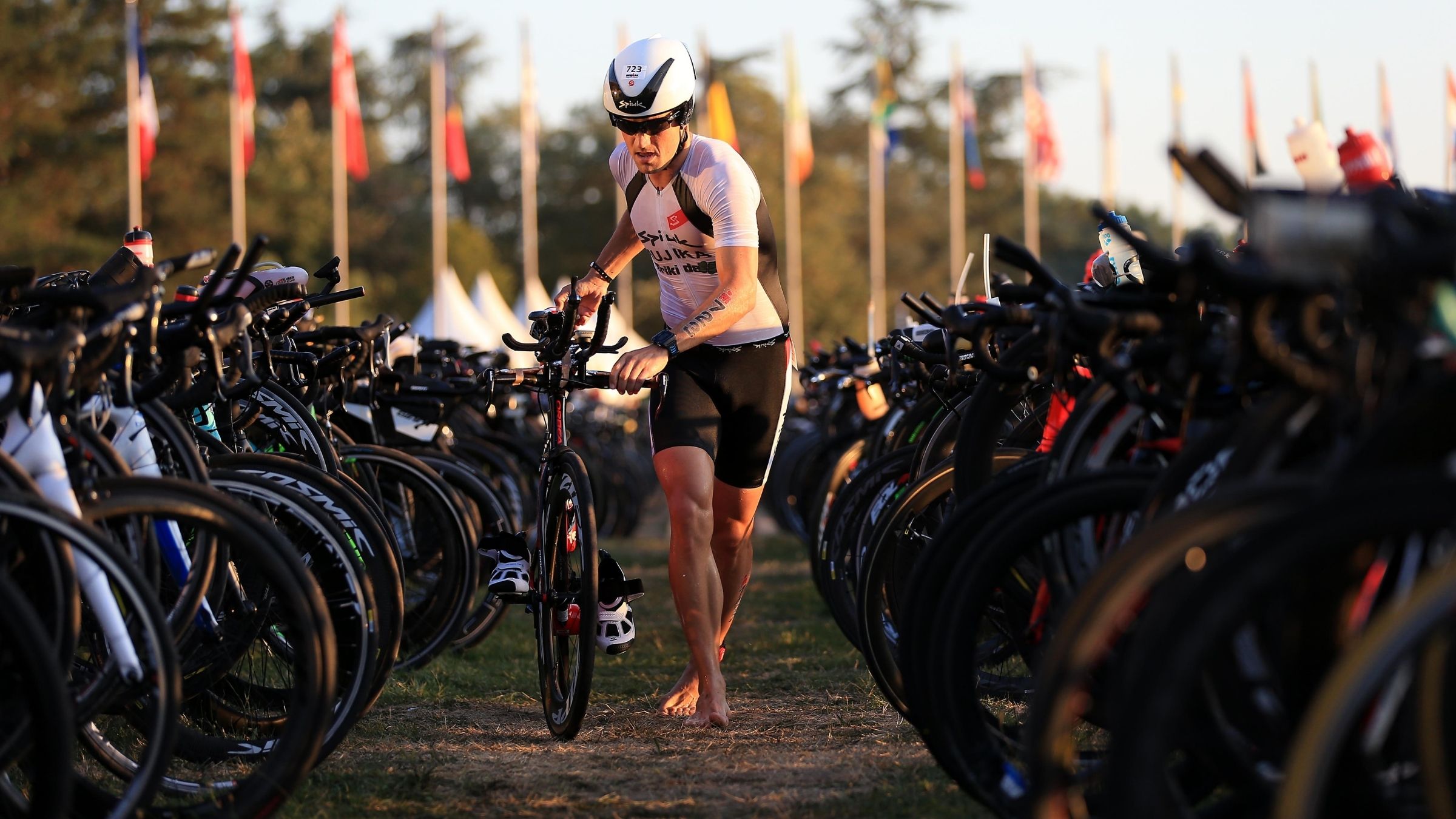 An athlete runs his bike through the transition area of a triathlon.