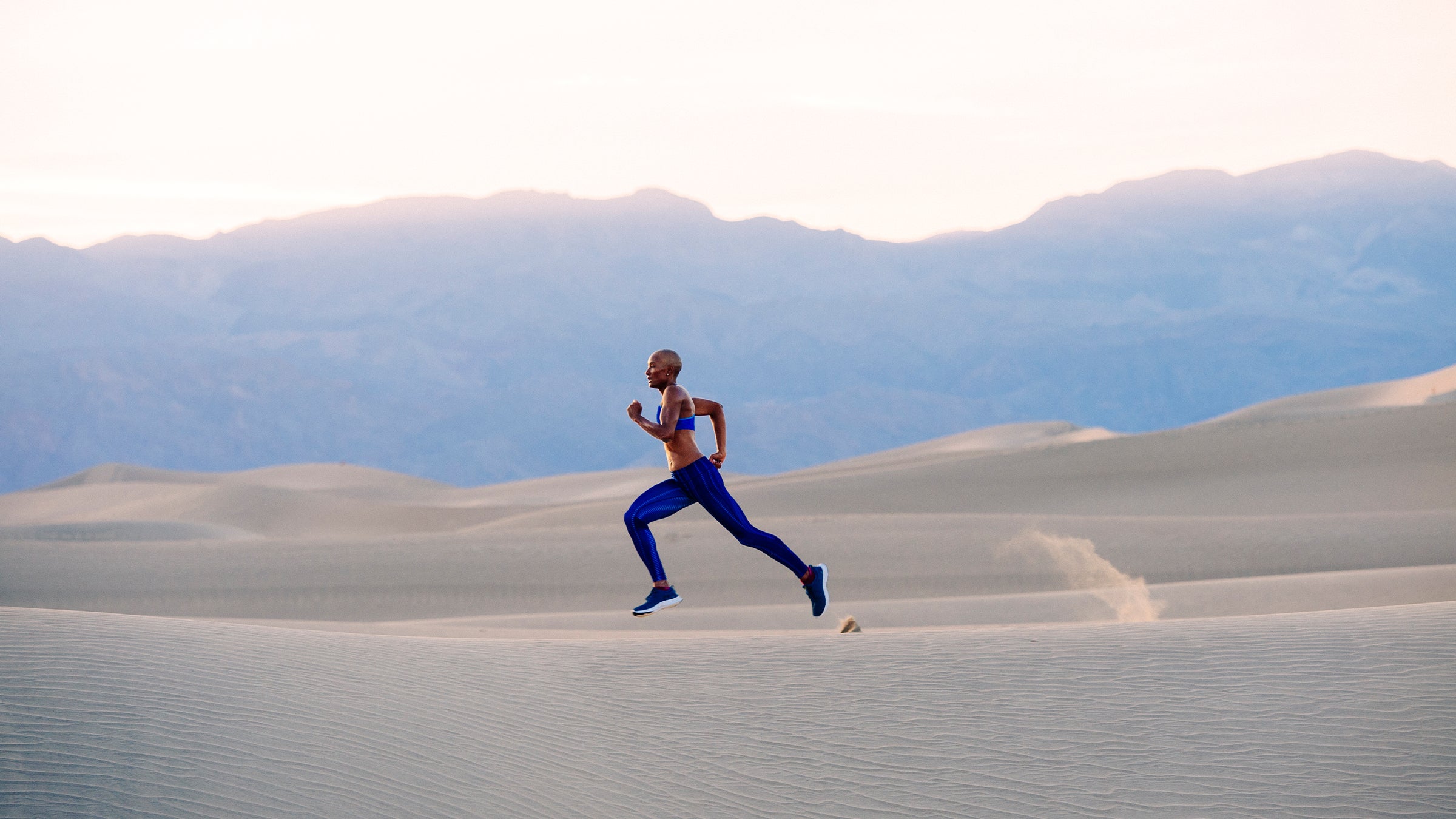 Woman running across sand dunes