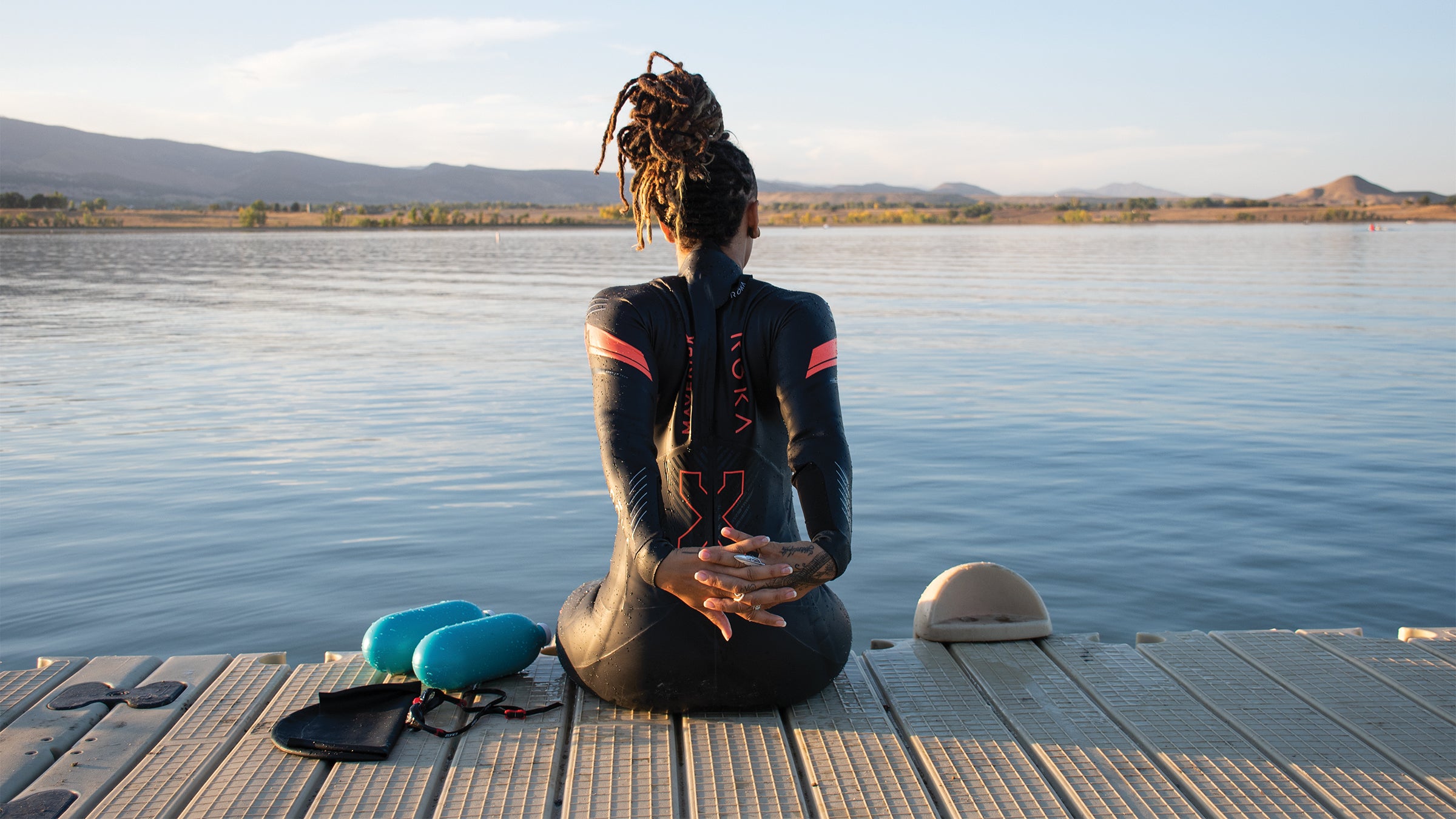 Woman in a wetsuit stretching before she swims in a reservoir