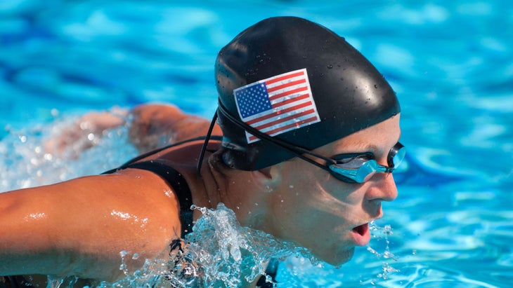 A swimmer in a swim cap with the American flag does the postal swim, a bucket-list swim workout for triathletes.