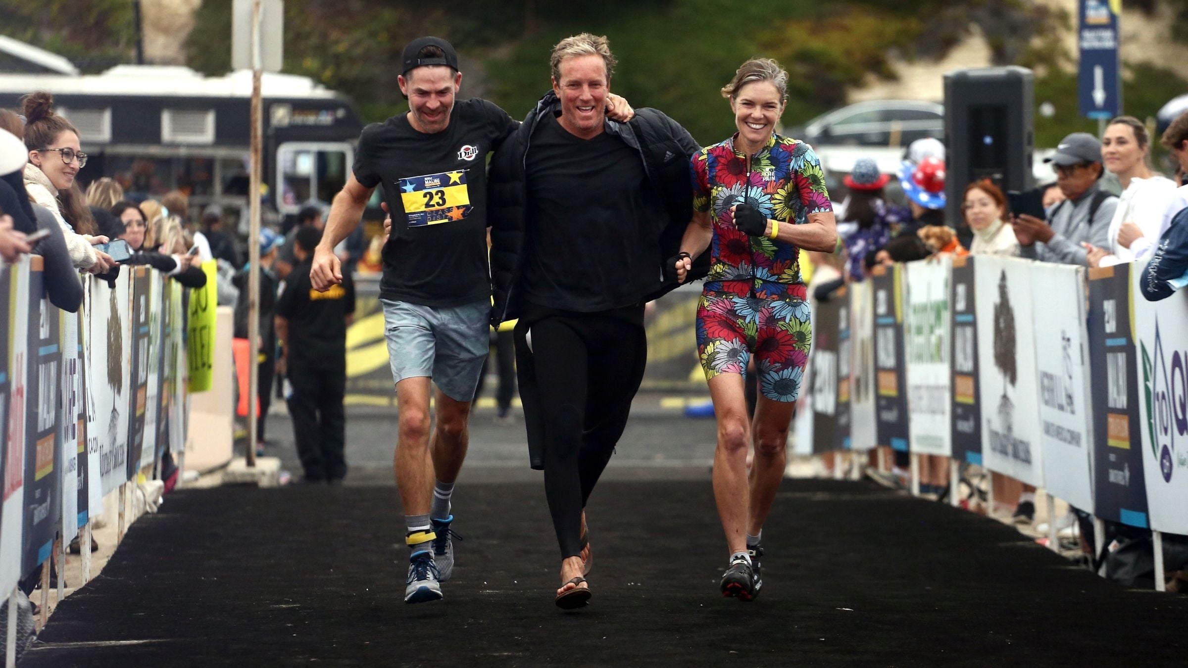 A triathlon relay team crosses the finish line together.