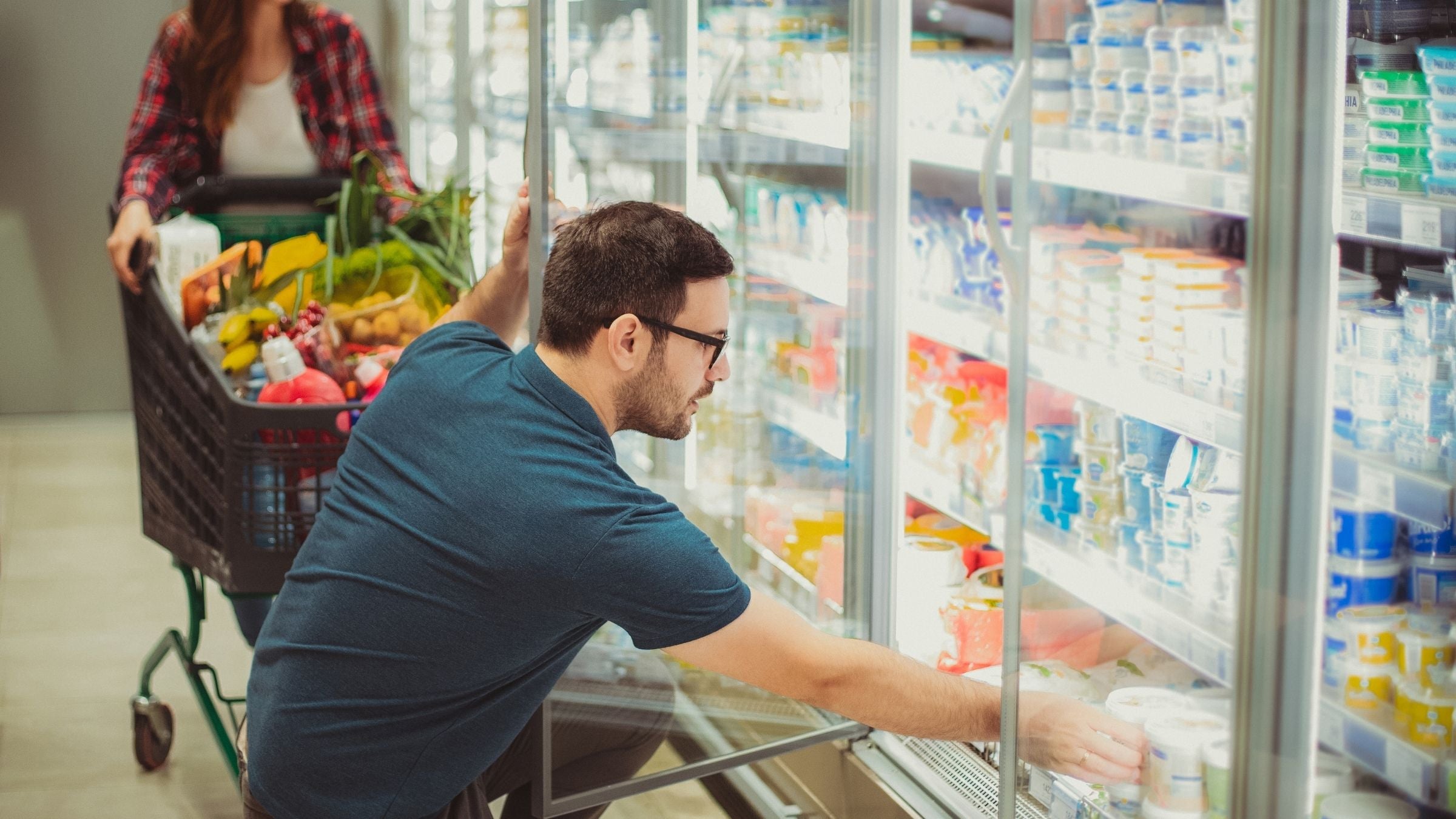 A man and a woman shop for cheap protein sources at the grocery store.