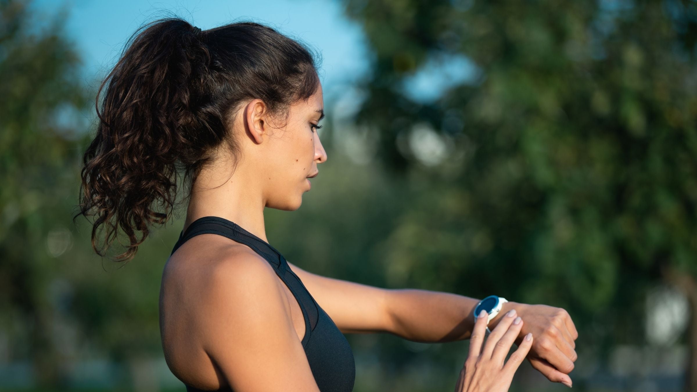 A woman looks at her sport watch before beginning a run for anxiety relief.