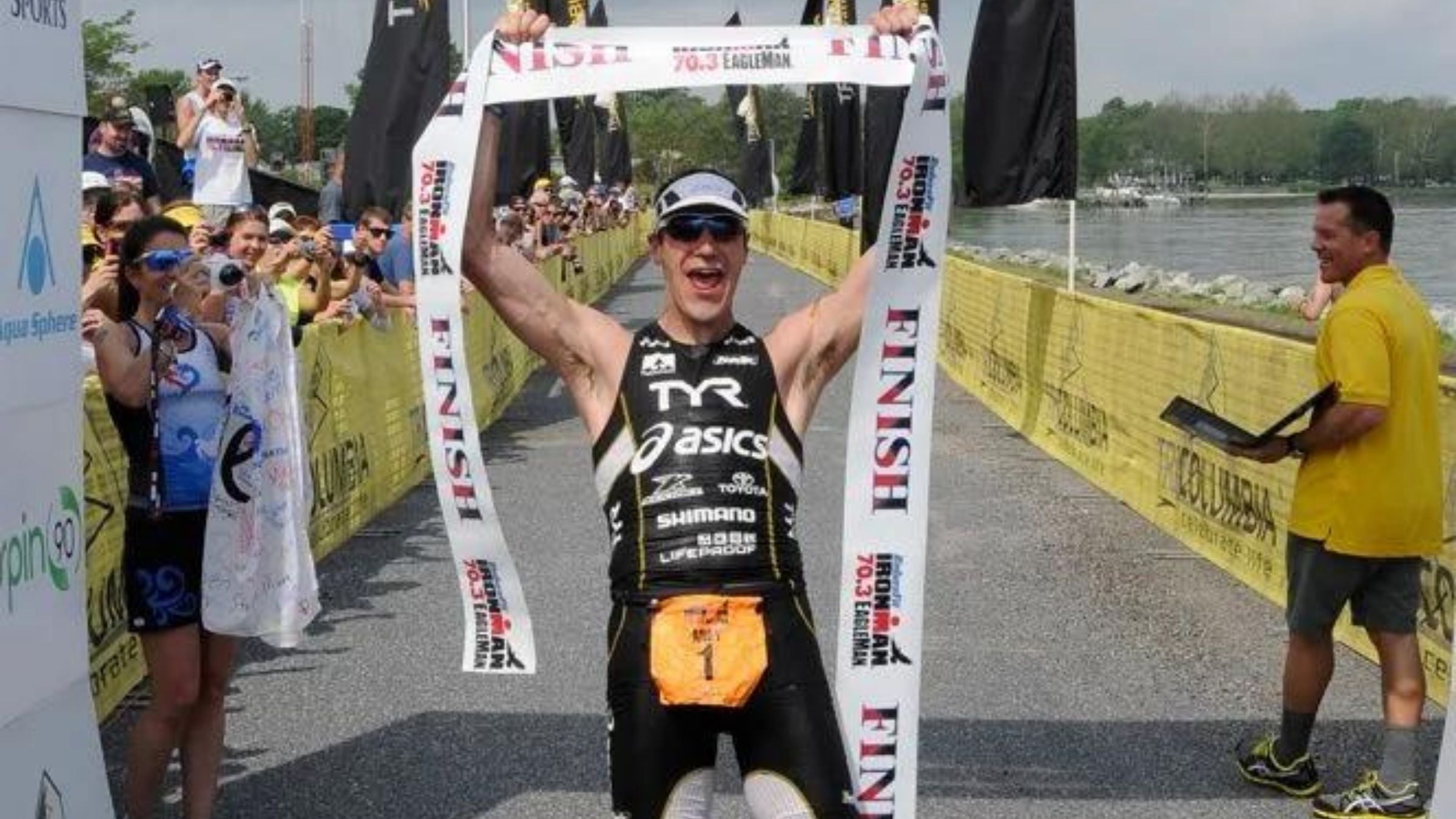 Andy Potts, a triathlete, holds up a finisher tape as he celebrates winning Ironman 70.3 Eagleman.