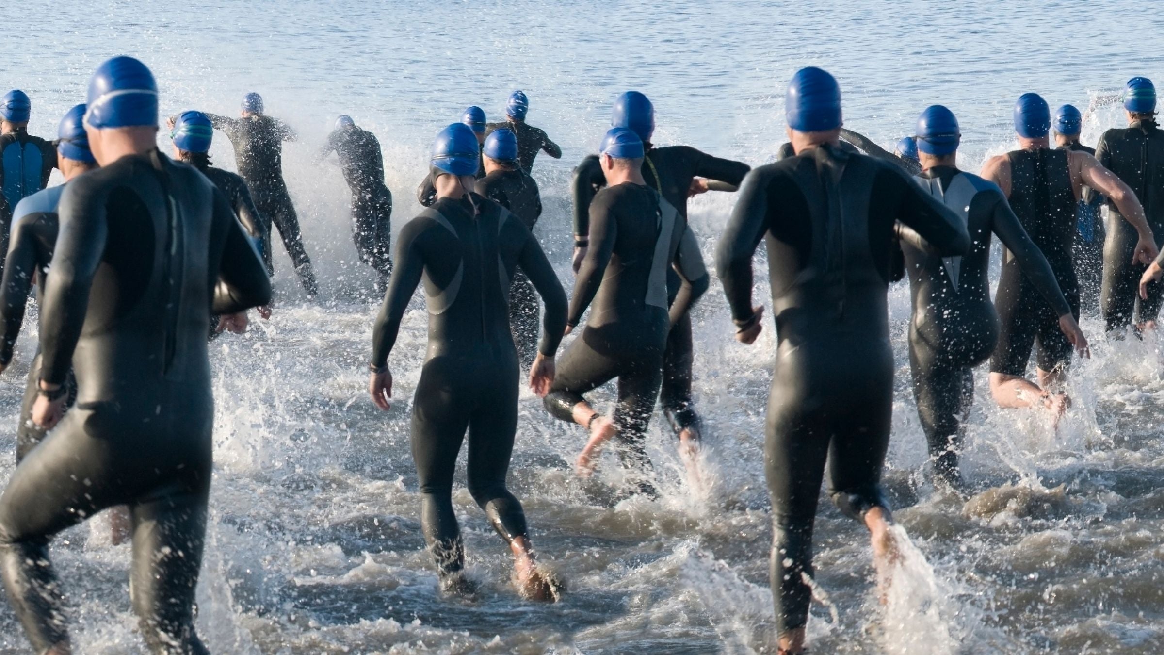 Triathletes enter the water to start their race. There are new rules and policies related to transgender athletes in triathlon.