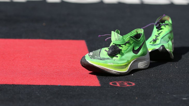 A pair of triathlon shoes with elastic shoe laces rests on the ground