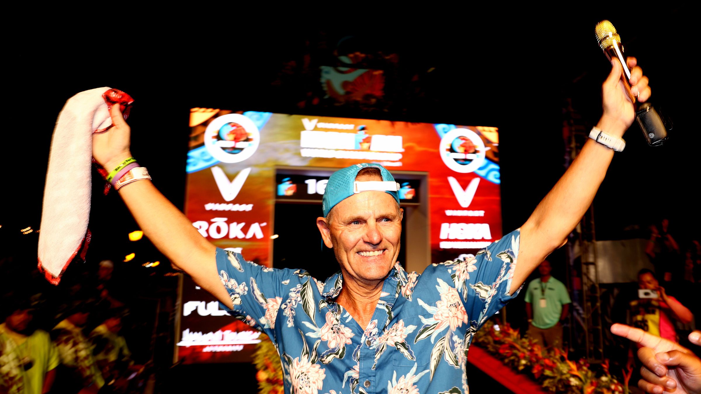 Mike Reilly waves as he calls his last Ironman race in Kona