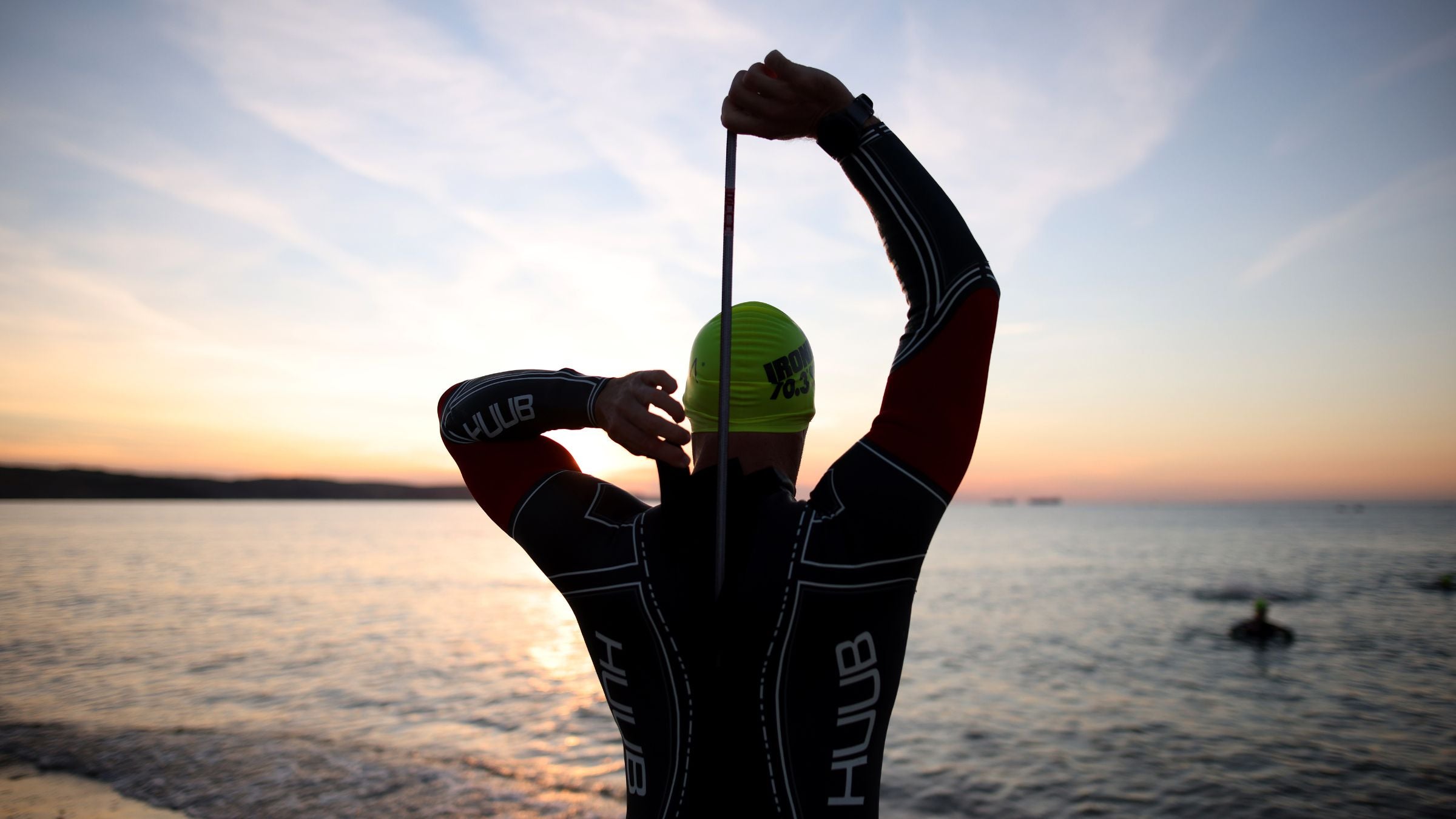 A triathlete zips up while wondering How much faster does a wetsuit make you swim?
