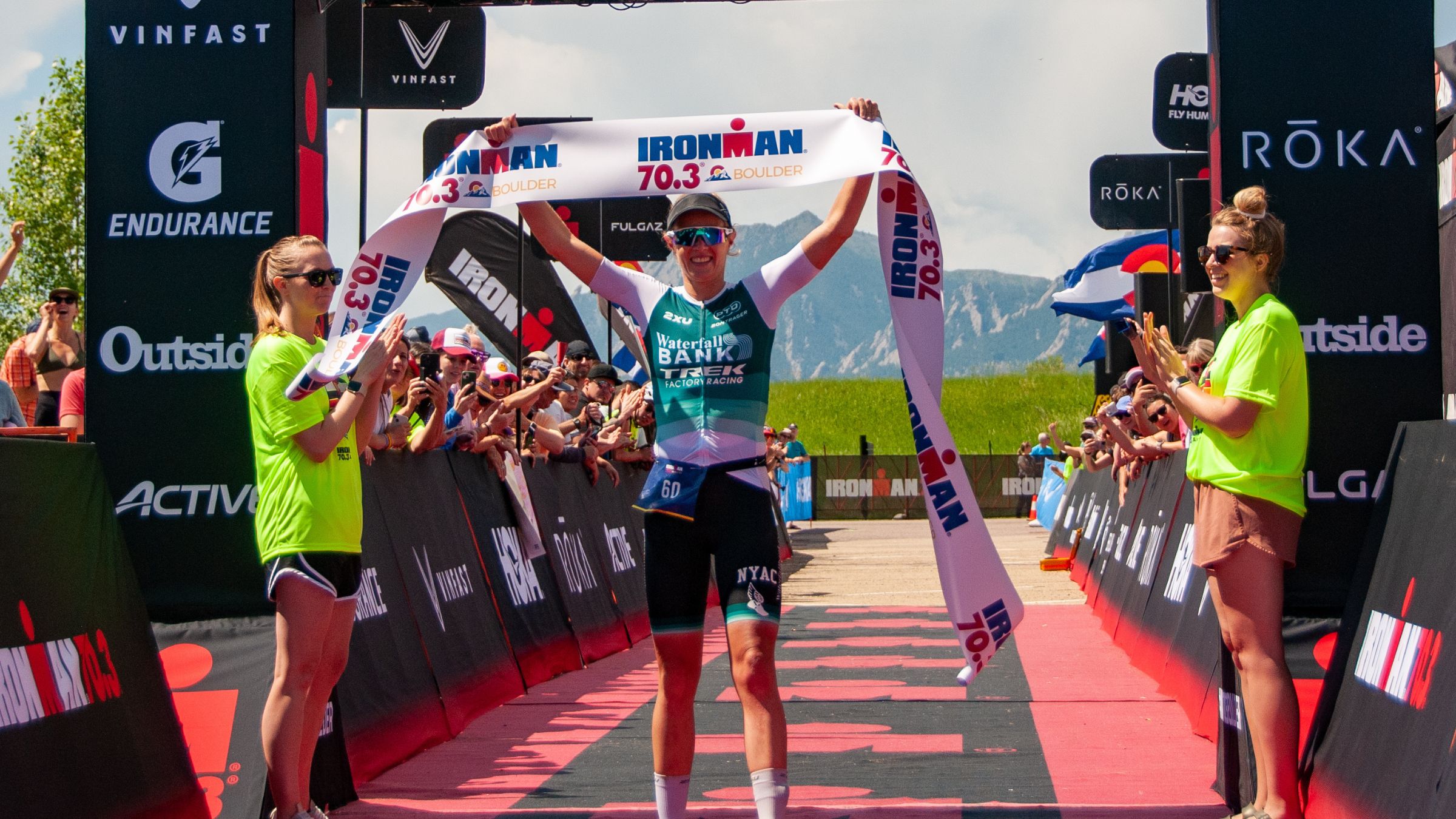 Taylor Knibb holds a finish line tape over her head after winning 70.3 Boulder 2023