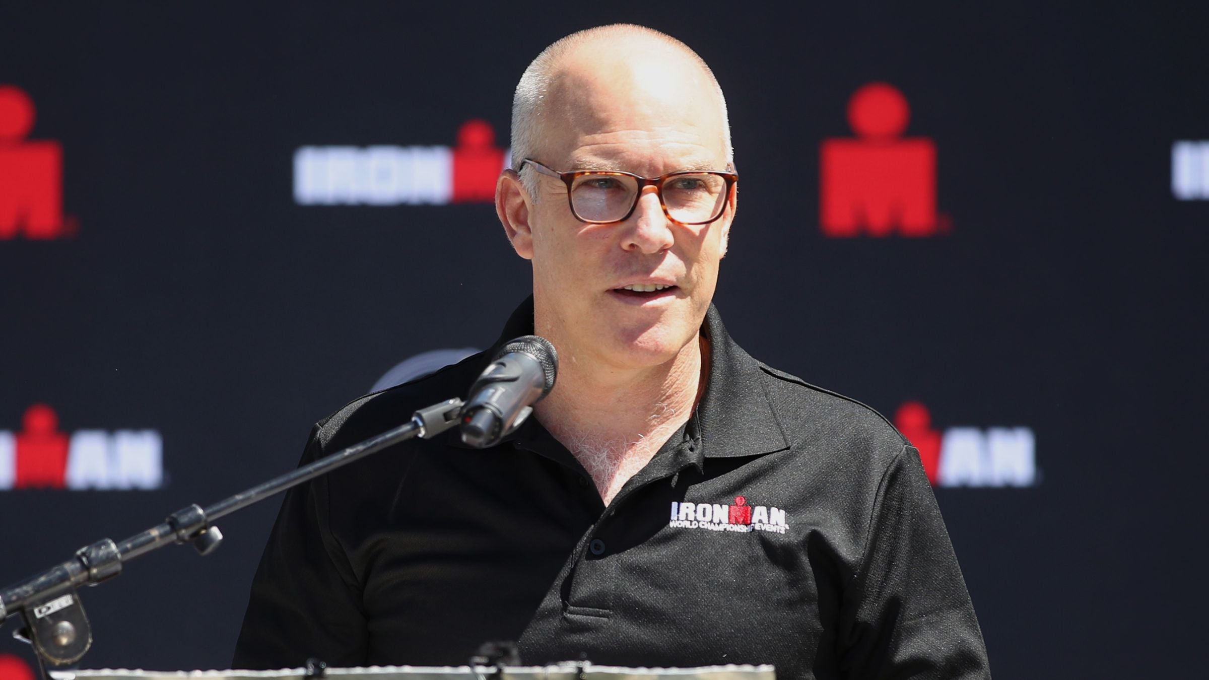 In breaking triathlon news, Ironman CEO Andrew Messick announced his retirement. In this photo, he makes a speech at a press conference.