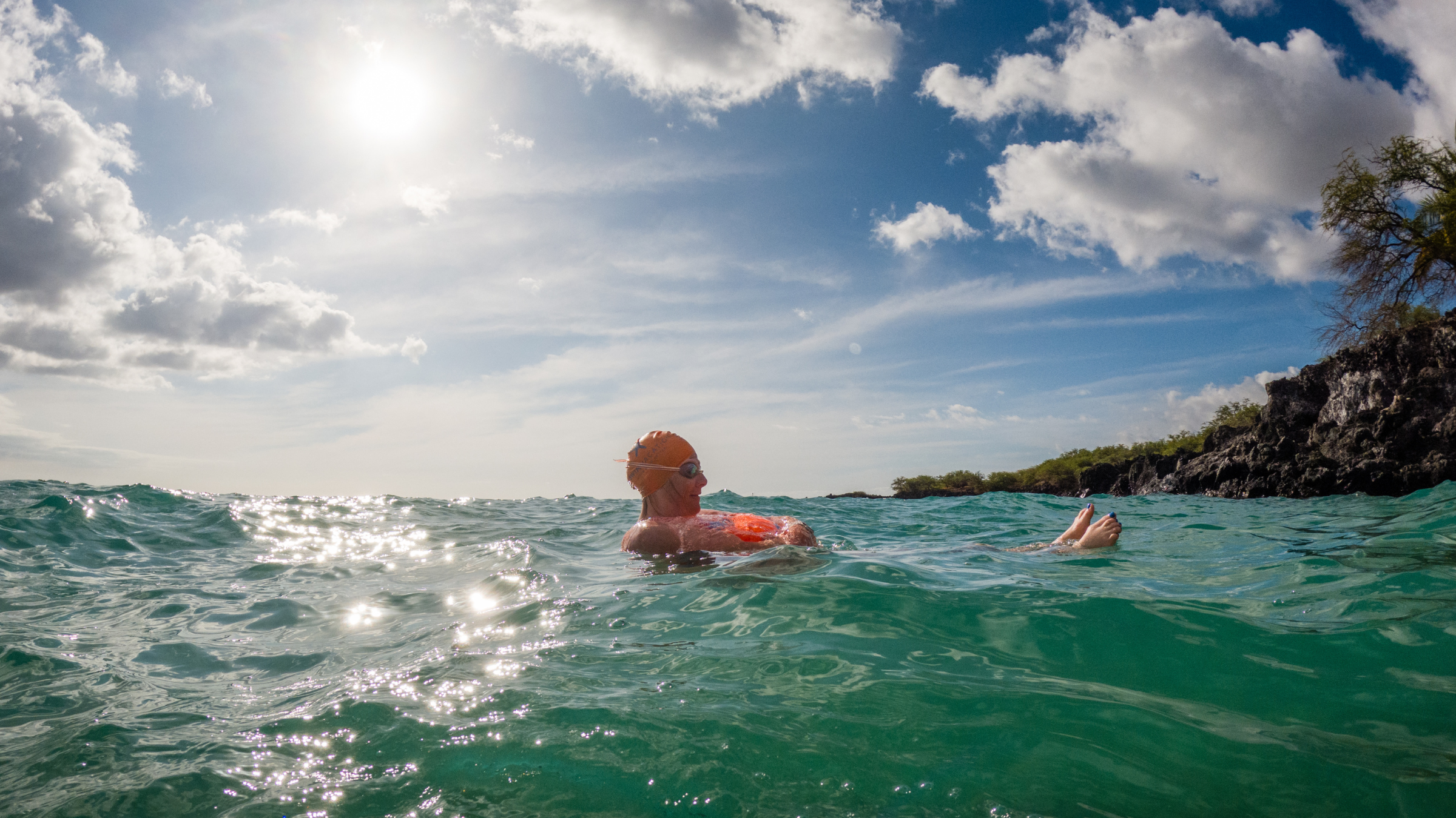 Woman floating in open water in Hawaii on swim vacation