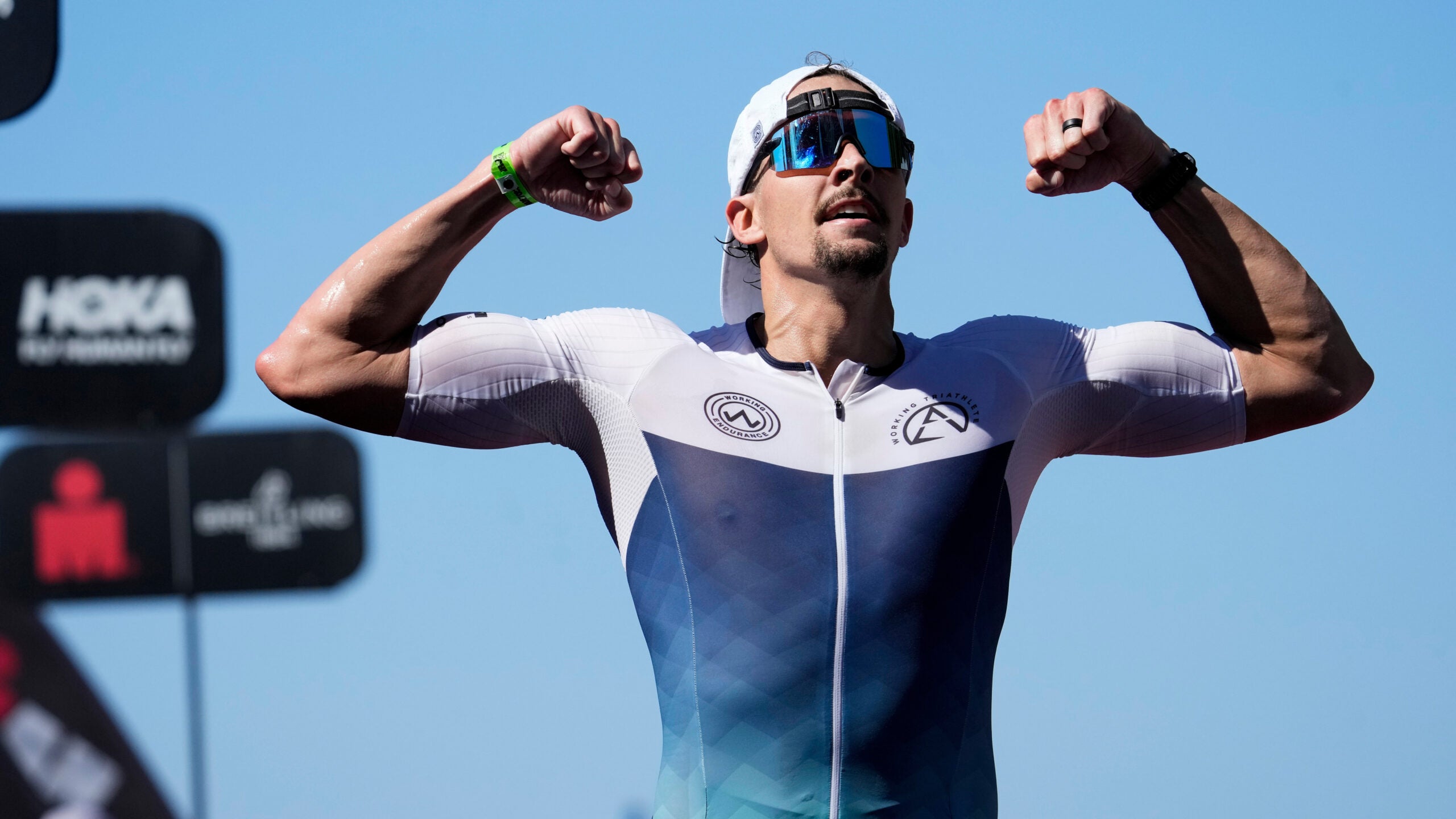 A male triathlete flexes at the finish line of Ironman 70.3 Michigan.